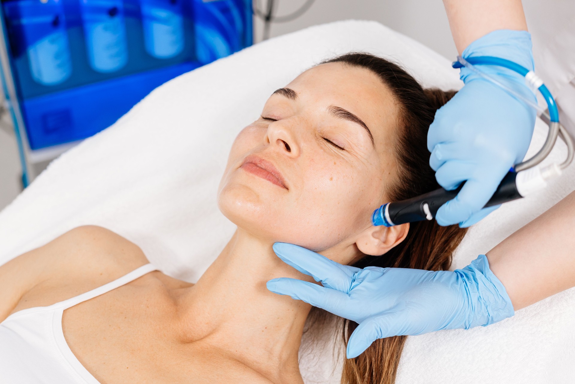 Close-up of a cosmetologist's hands polishing and cleansing the skin of a middle-aged woman's face using a vacuum machine. Concept of skin care, rejuvenation and cosmetology.